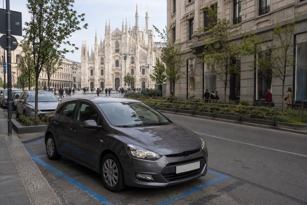 Auto auf einem blau markierten Parkplatz in Mailand mit dem Mailänder Dom im Hintergrund