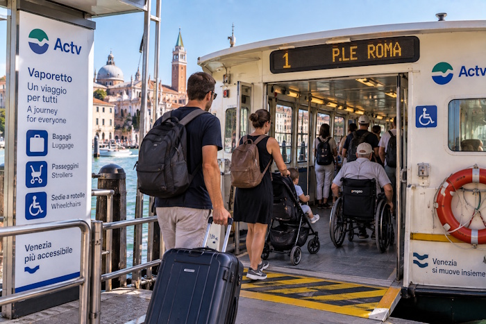 Vaporetto in Venedig mit Gepäck, Kinderwagen und Rollstuhl beim Einsteigen